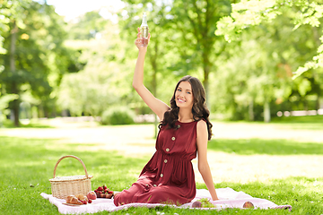 Image showing happy woman with picnic basket and drink at park