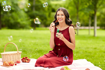 Image showing happy woman blowing soap bubbles at picnic