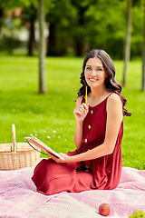 Image showing happy woman with diary and picnic basket at park
