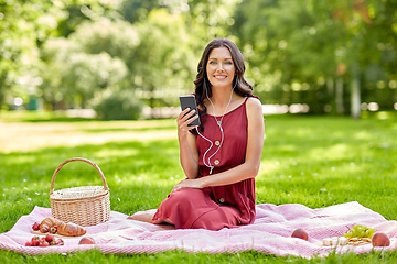 Image showing woman with smartphone and earphones at picnic