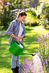 Image showing young woman watering flowers at garden