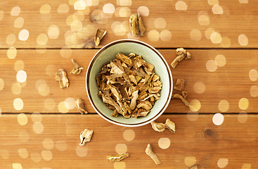 Image showing dried mushrooms in bowl on wooden background