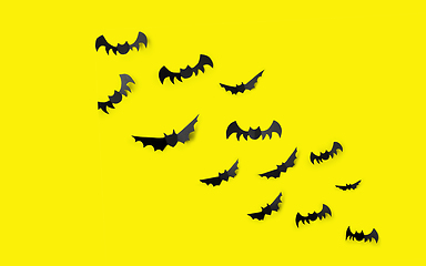 Image showing flock of black paper bats over yellow background