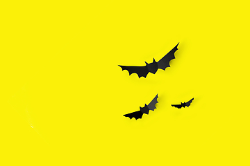 Image showing flock of black paper bats over yellow background