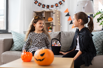 Image showing girls in halloween costumes with candies at home