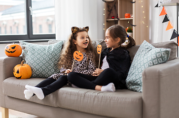 Image showing girls in halloween costumes with pumpkins at home