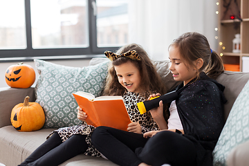 Image showing girls in halloween costumes reading book at home