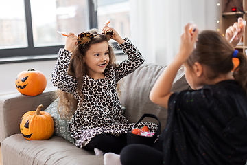 Image showing girls in halloween costumes with candies at home