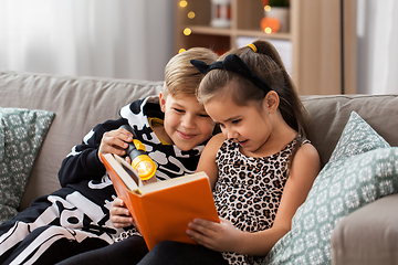 Image showing kids in halloween costumes reading book at home