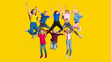 Image showing Portrait of little children jumping isolated on yellow studio background with copyspace