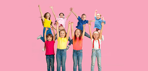 Image showing Portrait of little children jumping isolated on pink studio background with copyspace