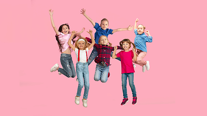 Image showing Portrait of little children jumping isolated on pink studio background with copyspace