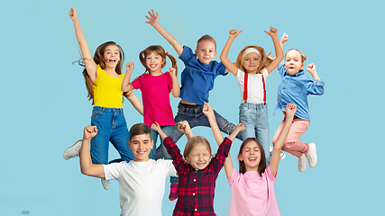 Image showing Portrait of little children jumping isolated on blue studio background with copyspace