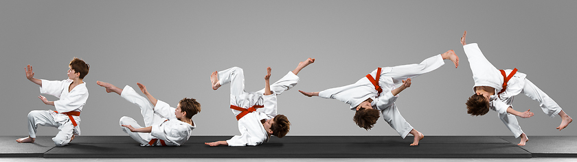 Image showing Young judo caucasian male fighter in white kimono with red belt in motion and action during training. Practicing martial arts fighting skills.