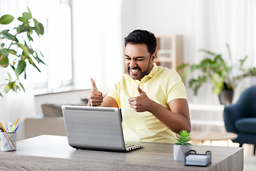 Image showing happy indian man with laptop at home office