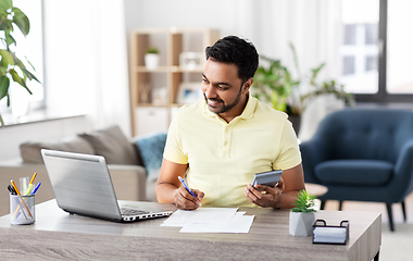 Image showing man with calculator and papers working at home