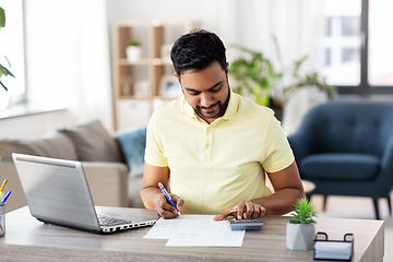 Image showing man with calculator and papers working at home