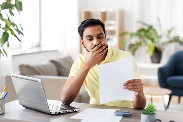 Image showing man with calculator and papers working at home