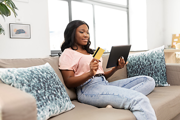 Image showing happy woman with tablet pc and credit card at home