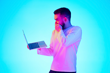 Image showing Caucasian man\'s portrait isolated on blue studio background in neon light. Concept of human emotions, facial expression, sales, ad.