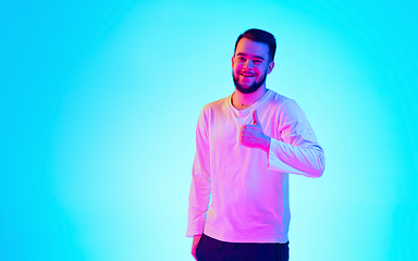 Image showing Caucasian man\'s portrait isolated on blue studio background in neon light. Concept of human emotions, facial expression, sales, ad.