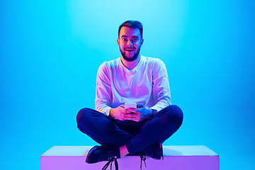 Image showing Caucasian man\'s portrait isolated on blue studio background in neon light. Concept of human emotions, facial expression, sales, ad.