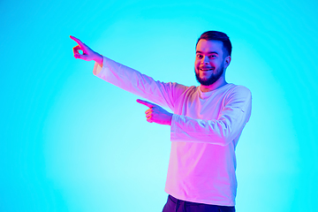 Image showing Caucasian man\'s portrait isolated on blue studio background in neon light. Concept of human emotions, facial expression, sales, ad.