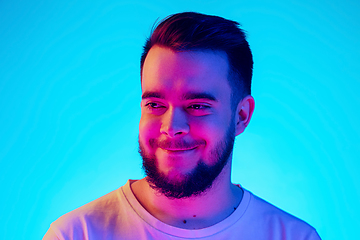 Image showing Caucasian man\'s portrait isolated on blue studio background in neon light. Concept of human emotions, facial expression, sales, ad.