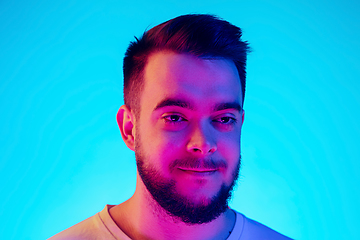 Image showing Caucasian man\'s portrait isolated on blue studio background in neon light. Concept of human emotions, facial expression, sales, ad.