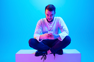 Image showing Caucasian man\'s portrait isolated on blue studio background in neon light. Concept of human emotions, facial expression, sales, ad.