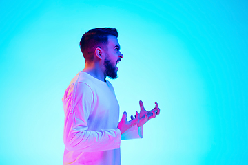 Image showing Caucasian man\'s portrait isolated on blue studio background in neon light. Concept of human emotions, facial expression, sales, ad.