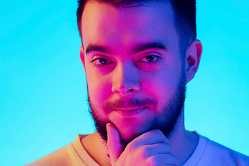 Image showing Caucasian man\'s portrait isolated on blue studio background in neon light. Concept of human emotions, facial expression, sales, ad.