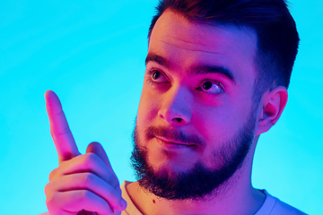 Image showing Caucasian man\'s portrait isolated on blue studio background in neon light. Concept of human emotions, facial expression, sales, ad.