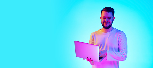 Image showing Caucasian man\'s portrait isolated on blue studio background in neon light. Concept of human emotions, facial expression, sales, ad.