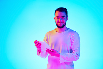 Image showing Caucasian man\'s portrait isolated on blue studio background in neon light. Concept of human emotions, facial expression, sales, ad.