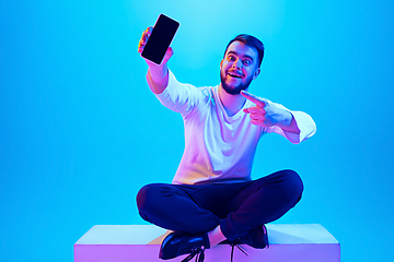 Image showing Caucasian man\'s portrait isolated on blue studio background in neon light. Concept of human emotions, facial expression, sales, ad.