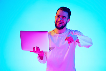 Image showing Caucasian man\'s portrait isolated on blue studio background in neon light. Concept of human emotions, facial expression, sales, ad.