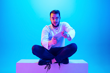 Image showing Caucasian man\'s portrait isolated on blue studio background in neon light. Concept of human emotions, facial expression, sales, ad.