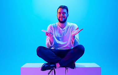 Image showing Caucasian man\'s portrait isolated on blue studio background in neon light. Concept of human emotions, facial expression, sales, ad.