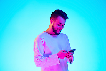 Image showing Caucasian man\'s portrait isolated on blue studio background in neon light. Concept of human emotions, facial expression, sales, ad.