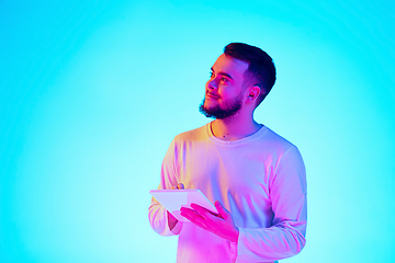 Image showing Caucasian man\'s portrait isolated on blue studio background in neon light. Concept of human emotions, facial expression, sales, ad.