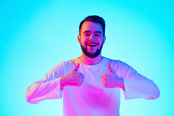 Image showing Caucasian man\'s portrait isolated on blue studio background in neon light. Concept of human emotions, facial expression, sales, ad.