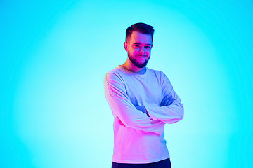 Image showing Caucasian man\'s portrait isolated on blue studio background in neon light. Concept of human emotions, facial expression, sales, ad.