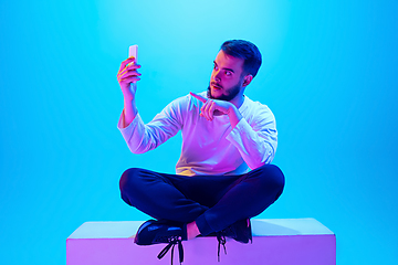 Image showing Caucasian man\'s portrait isolated on blue studio background in neon light. Concept of human emotions, facial expression, sales, ad.