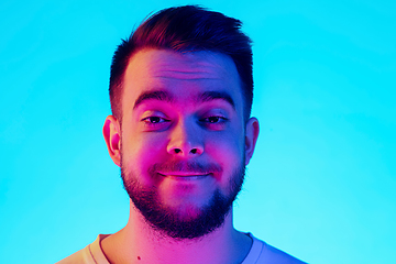 Image showing Caucasian man\'s portrait isolated on blue studio background in neon light. Concept of human emotions, facial expression, sales, ad.