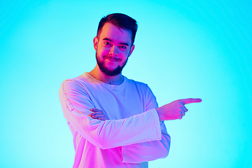 Image showing Caucasian man\'s portrait isolated on blue studio background in neon light. Concept of human emotions, facial expression, sales, ad.