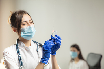 Image showing Doctor or nurse giving vaccine to patient using the syringe injected in hospital