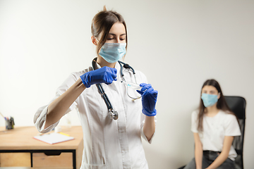 Image showing Doctor or nurse giving vaccine to patient using the syringe injected in hospital