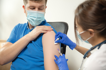 Image showing Close up doctor or nurse giving vaccine to patient using the syringe injected in hospital