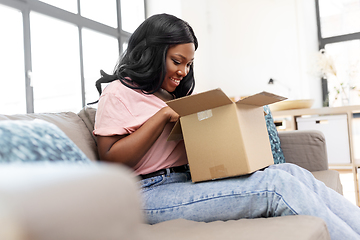 Image showing african american woman opening parcel box at home